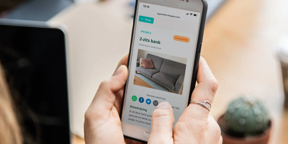 Vrouw bezoekt op haar telefoon de website van Goods for Refugees en kijkt naar een advertentie waar een bank aangeboden wordt