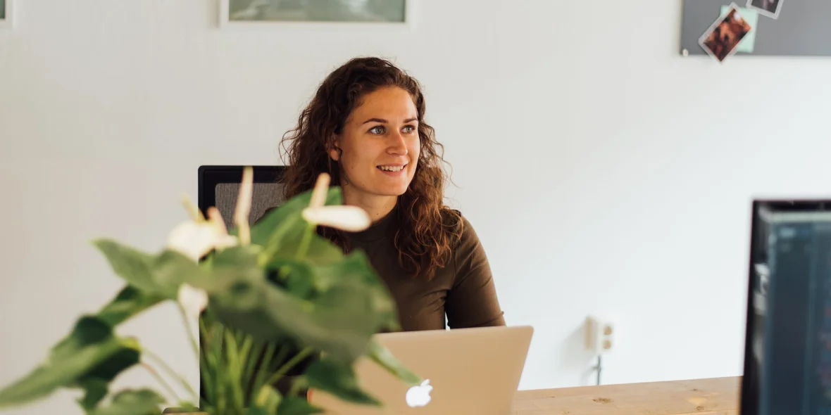 Medewerker zit aan haar bureau en is aan het werk op haar laptop
