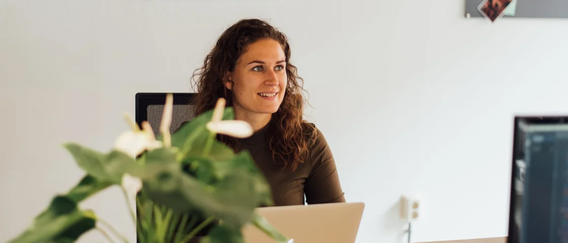 Medewerker zit aan haar bureau en is aan het werk op haar laptop