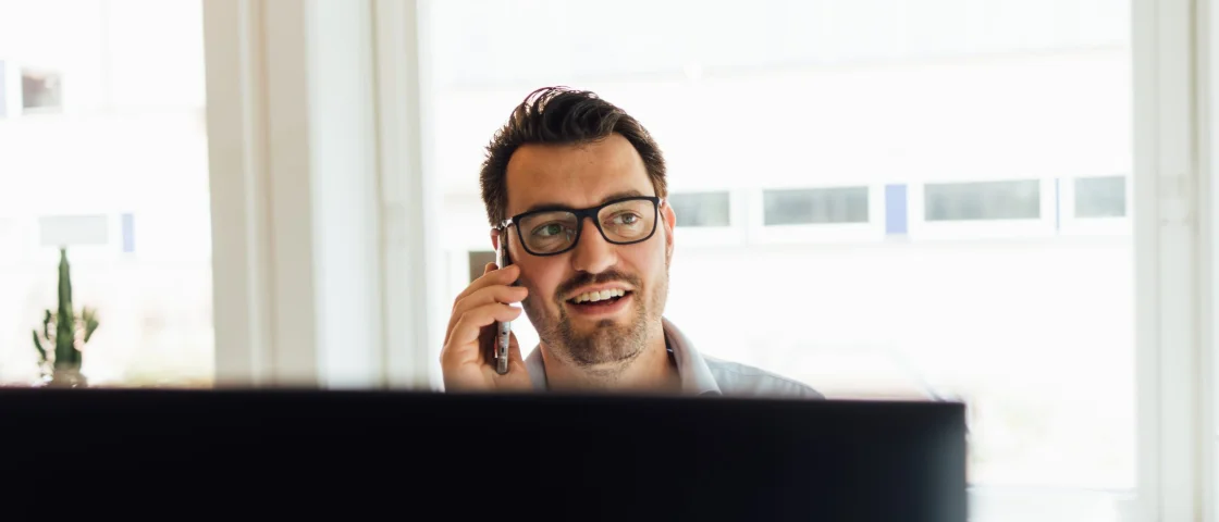 Reinier zit aan zijn bureau en belt