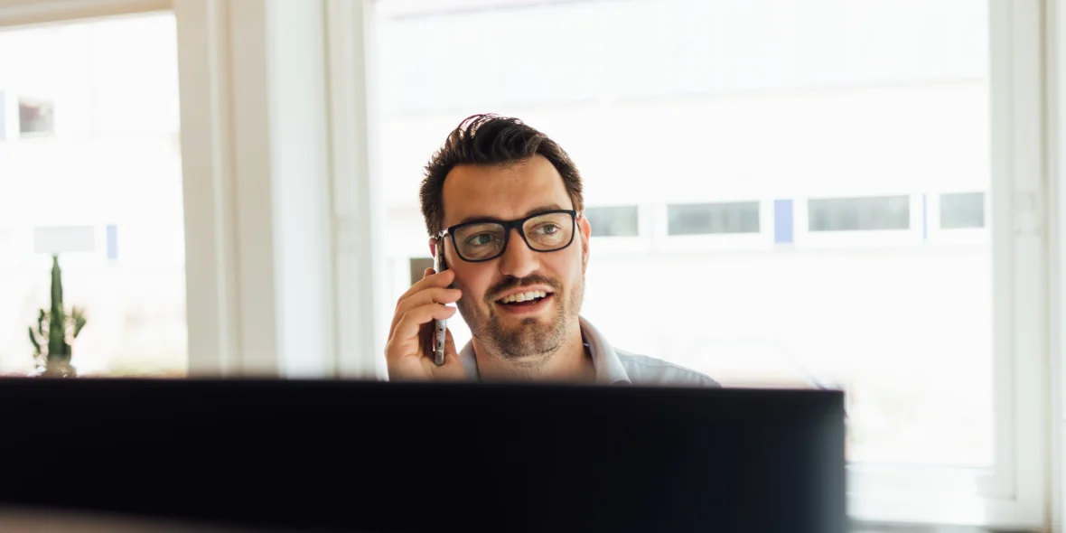 Reinier zit aan zijn bureau en belt