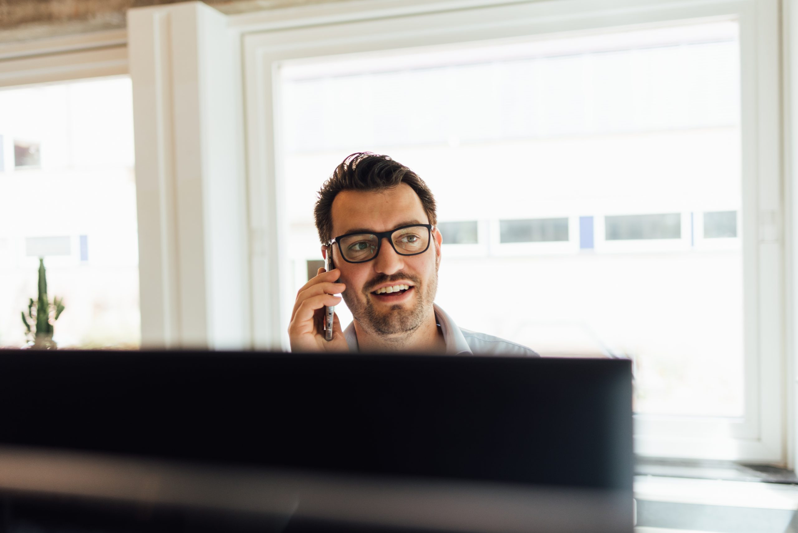 Reinier zit aan zijn bureau en belt