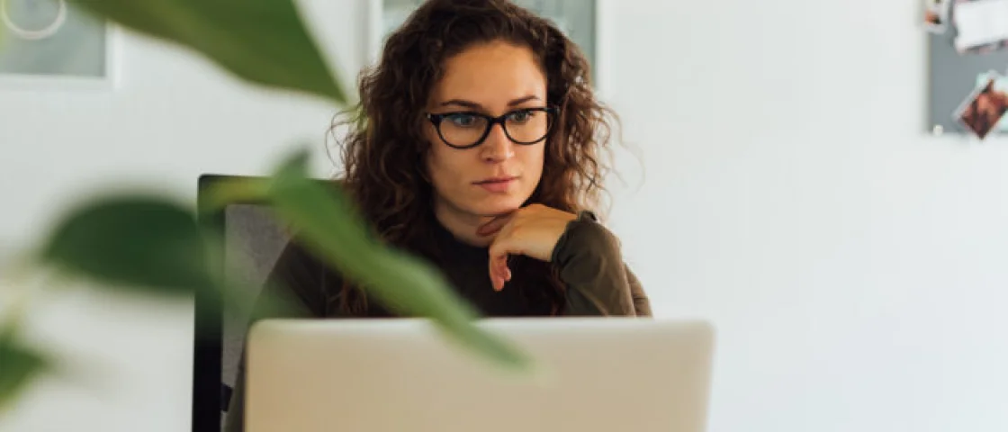 Vrouw met bril op werkt aan haar bureau aan haar computer