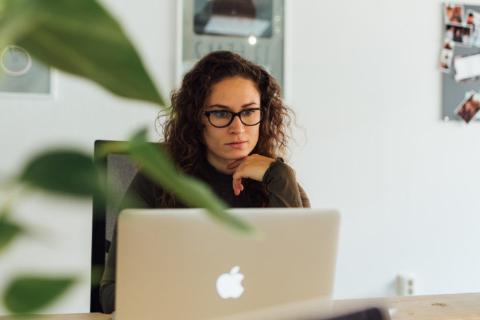 Vrouw met bril op werkt aan haar bureau aan haar computer