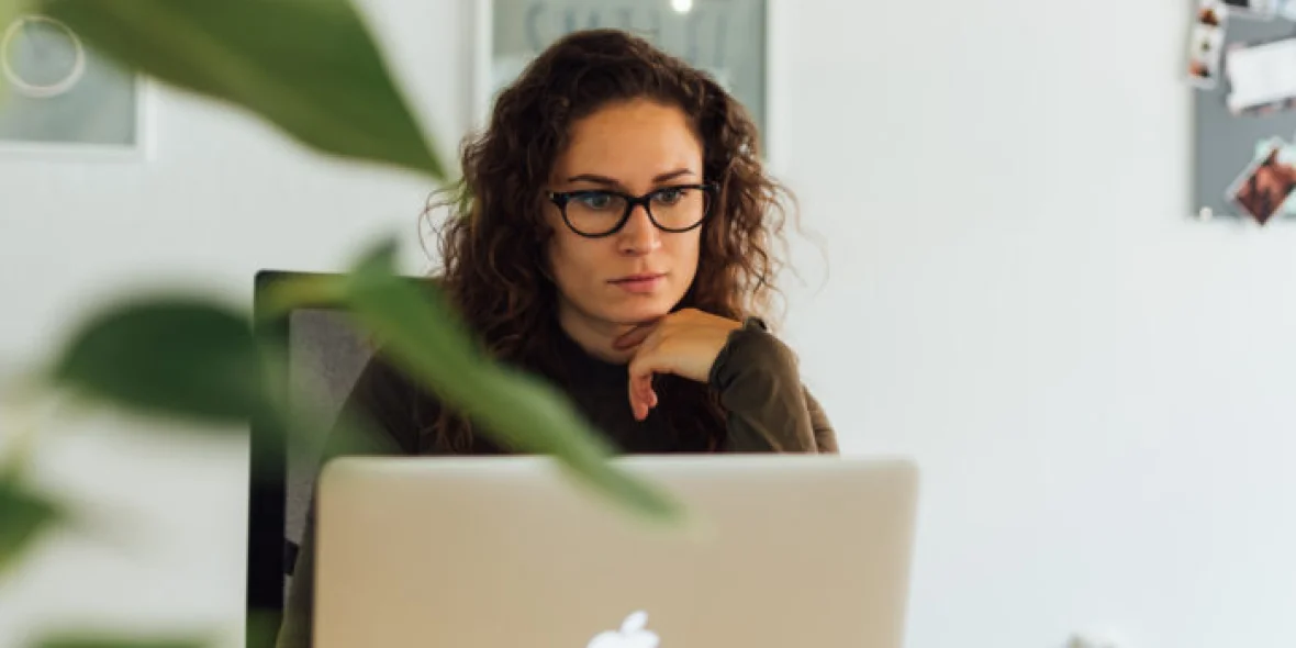 Vrouw met bril op werkt aan haar bureau aan haar computer