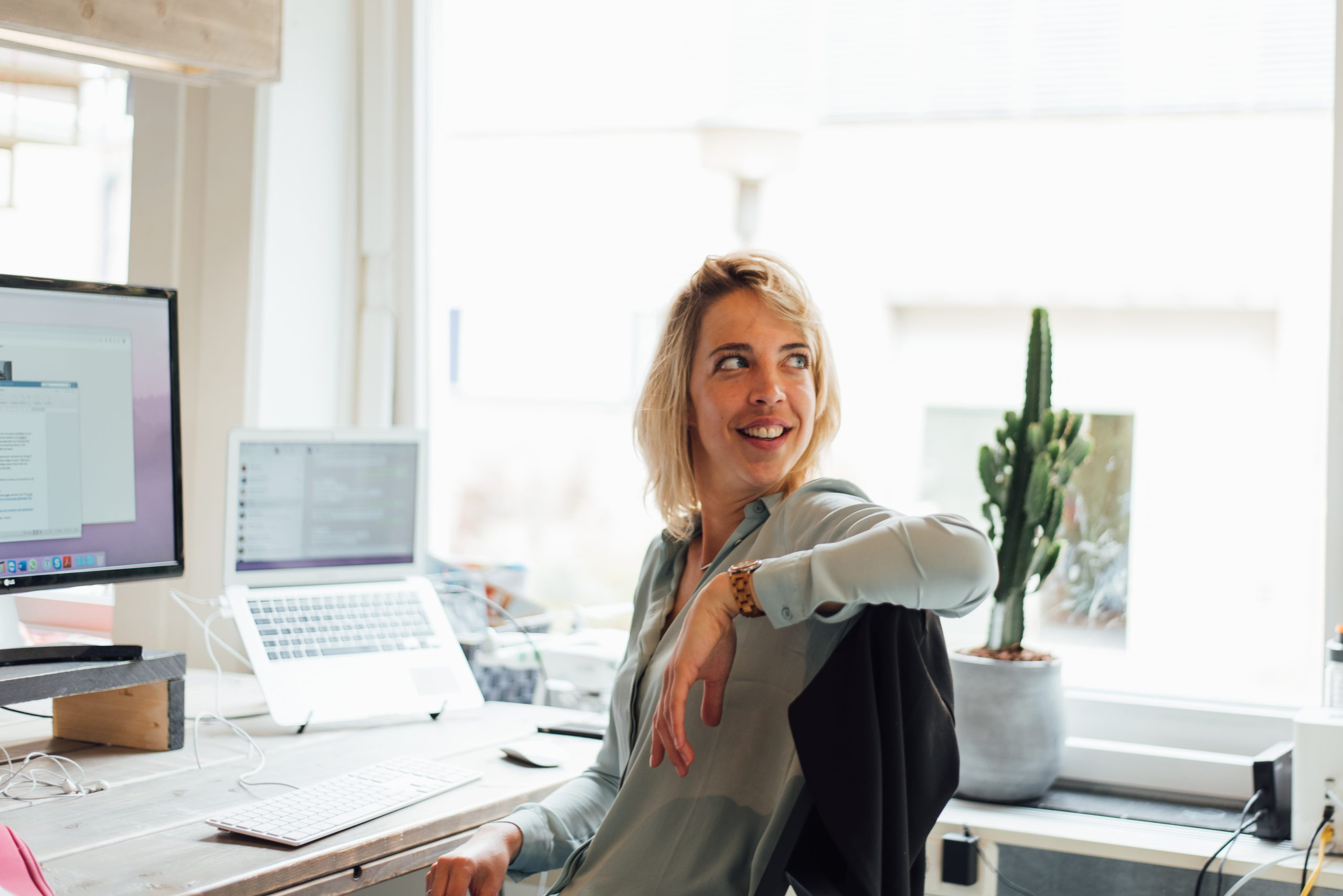 Carly aan haar bureau naar achter kijkend