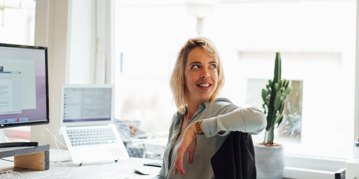 Carly aan haar bureau naar achter kijkend