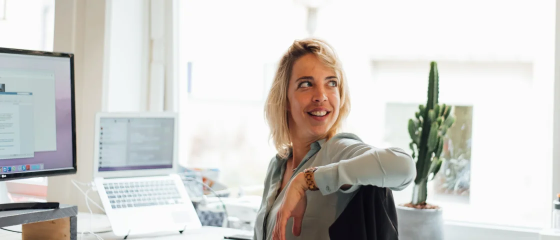 Carly aan haar bureau naar achter kijkend
