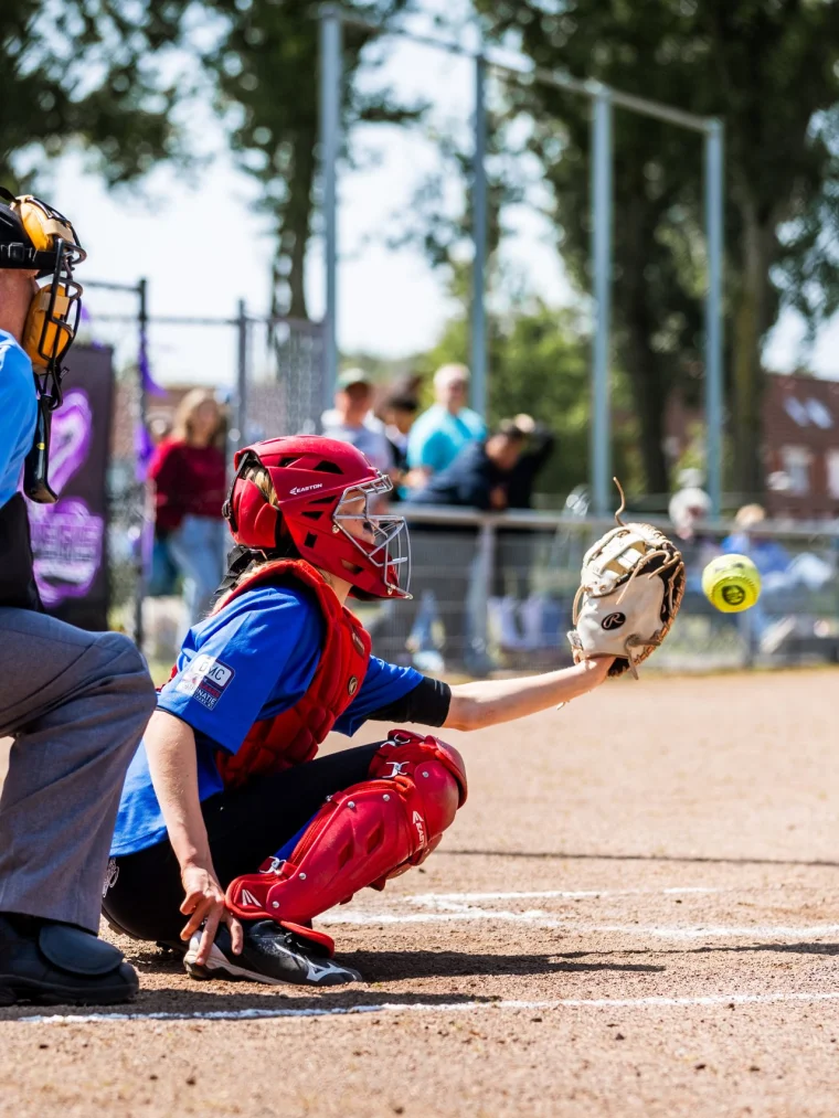 Een afbeelding van een Softbal catcher die een bal vangt