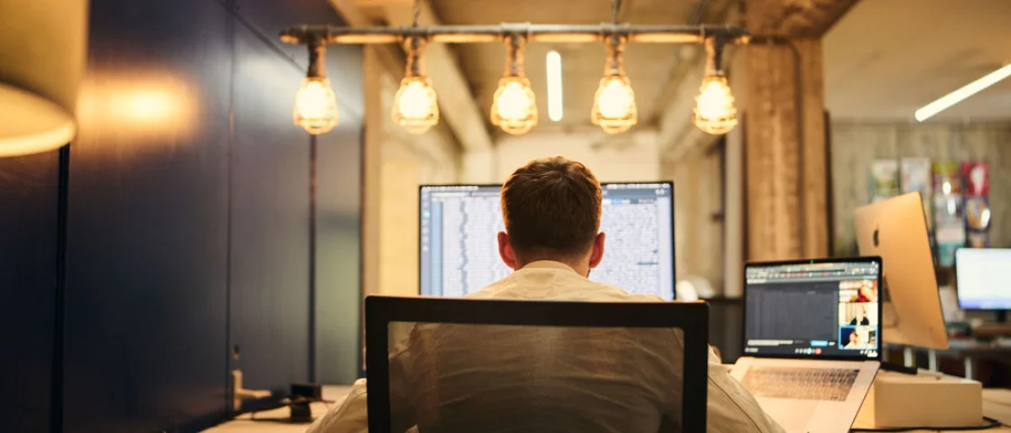 Een medewerker van Kobalt zit aan zijn bureau en is aan het werk op zijn computer met zijn rug naar de camera