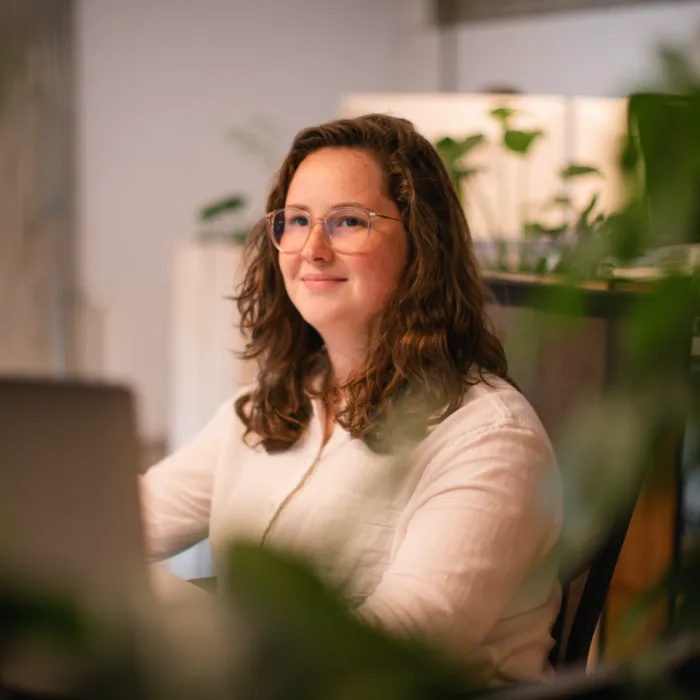 Kobalt-collega Roos lacht achter haar werkplek tussen de planten