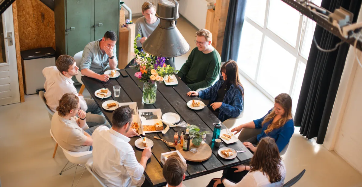 Het Kobalt-team zit samen aan tafel met taart, van bovenaf gefotografeerd