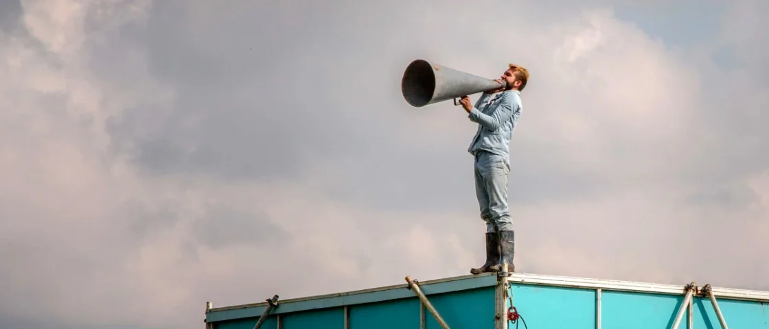 Man met luidspreker bovenop een gebouw