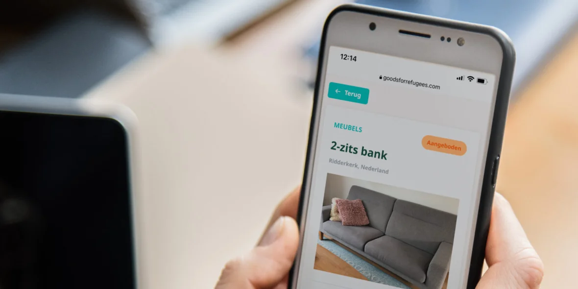 Afbeelding van een mobiel met daarop de goodsforrefugees website open op een advertentie waar een bank wordt aangeboden