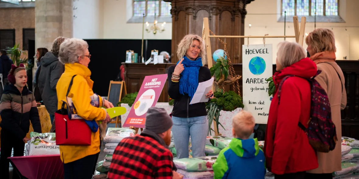 Vrouw bij een Upfest kraam met verschillende mensen eromheen.