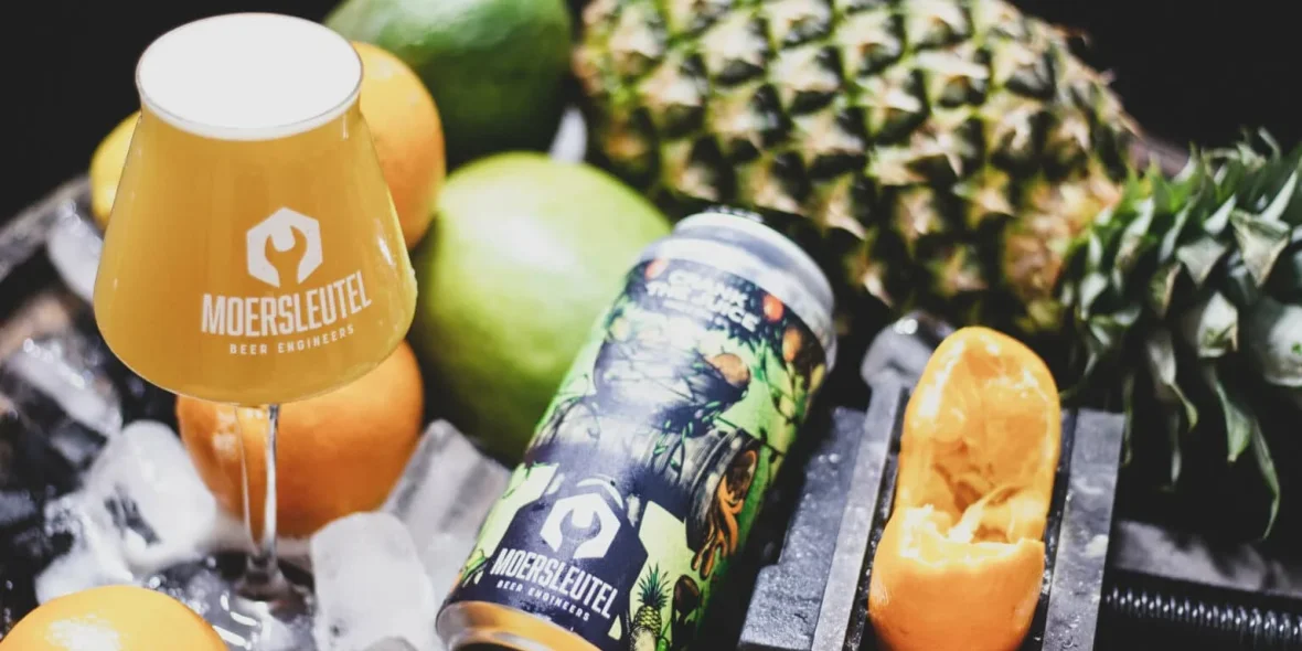 Blik van Crank the Juice en glas van Moersleutel omringd door fruit en ijs. Er wordt een sinaasappel geperst.